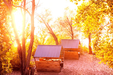 Two pavilions in the park near the river. A place to relax. Wooden summer houses. City park in autumn at sunset
