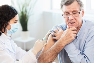 Brazilian nurse doing vaccination to senior man