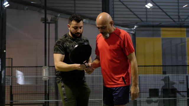 Son teaches his father how to perform a tennis paddle kick and how to position himself