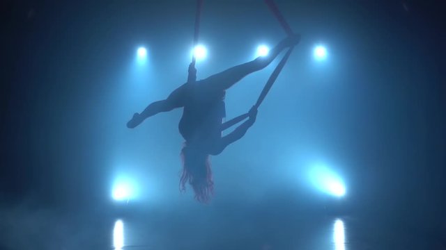 Graceful gymnast performing exercise with red silk on blue light background. Slow motion. 172