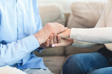 Happy elderly couple holding hands at home