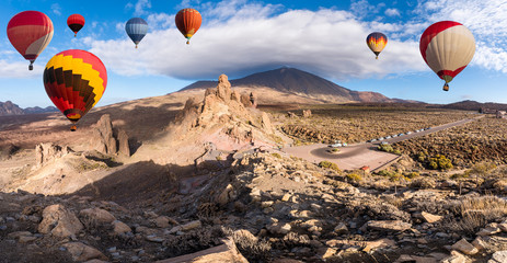 Obraz premium Landscape with hot air balloons flying in Teide National Park, Tenerife, Canary Islands, Spain. In background Roques de Garcia stone and Teide mountain volcano