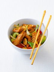 Asiatisch gebratene Hühnerbrust mit Gemüse in einer Schale mit Stäbchen