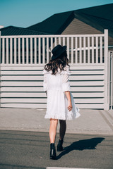 lifestyle portrait of young stylish hipster woman, wearing trendy white dress