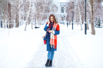 Fototapeta na wymiar Portrait of young girl in blue jeans walking in a winter park