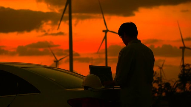 Engineer with laptop in front of wind turbines