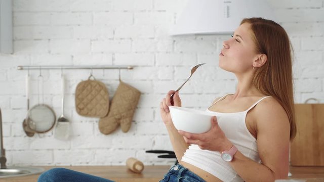 A vegetarian girl sits in the kitchen and eats salad from a plate. Healthy diet for weight loss.