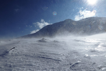Fototapeta na wymiar Whirlwind on snowy hilss in Slovakia Low Tatras. Epic wind storm in january with clear sky. Frozen land and snow attack on skier from side. Unpleasant side wind.