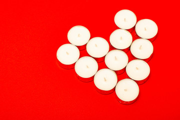Heart of white candles on a red background.