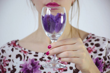 Young woman holding a wine glass filled with purple petals
