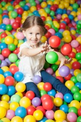Young girl in ball pit throwing colored balls