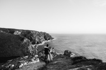 couple hug near ocean black and white