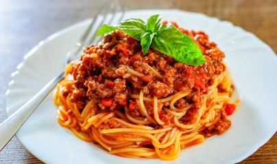 Traditional pasta spaghetti bolognese in white plate on wooden table background