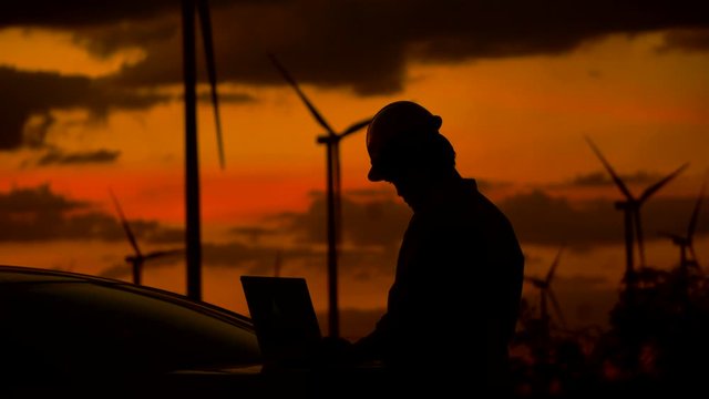 Engineer with laptop in front of wind turbines