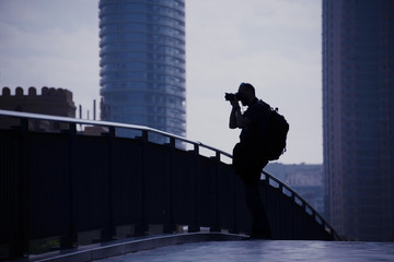 Silhouette of the street photographer with his camera and the backpack.