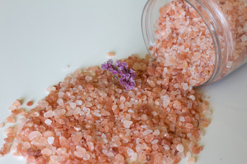 Fototapeta na wymiar Cosmetology, Spa and beauty products, the concept of beauty, recreation and health. Himalayan bath salt on a white background with a flower. The industry of beauty and relaxation.