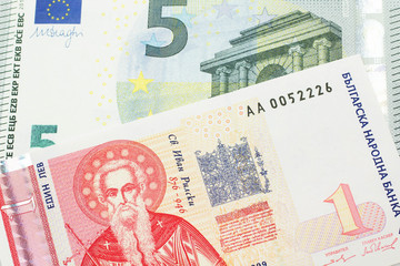 A Bulgarian one lev bank note with a red five euro German bank note close up in macro
