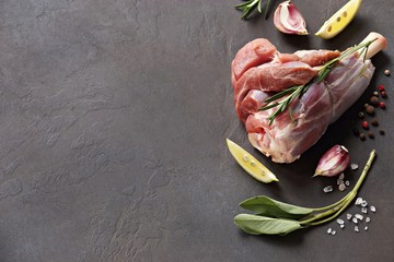Raw lamb shanks with herbs and spices. Flat layot on dark concrete background. Copy space