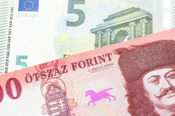 A close up image of a red, one hundred Hungarian forint bill close up with a blue and green five euro note from Germany in macro