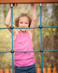 Half-length shot of young girl on climbing net