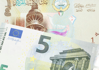 A one quarter dinar from Kuwait close up with a red European Union five euro note in macro