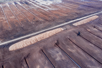 Aerial view over the peat quarry. Agricultural field, turf farm, brown soil. Bog drainage.