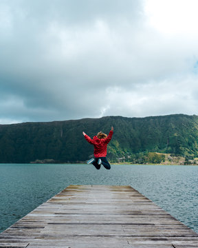 Young woman jumping on the jetty of a lake in Azores