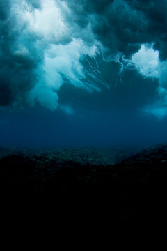 underwater shot of a wave breaking in Fiji, looking like a storm sky