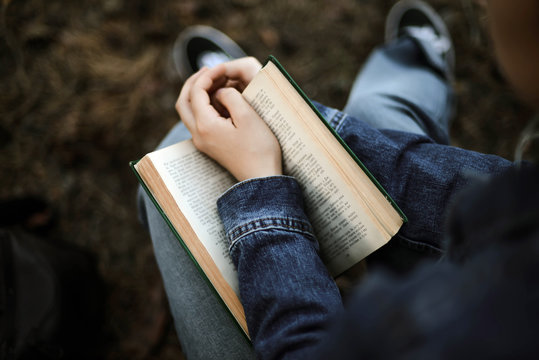 Woman reading a book sitting in the forest
