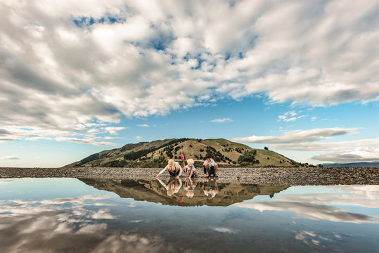 Three children exploring at low tide framed by mountain and reflection