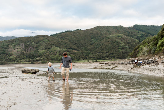 Father and young son walking in shallow water in New Zealand