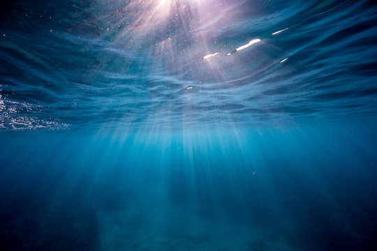 Sunrise piercing through clear blue waters in Oahu, Hawaii