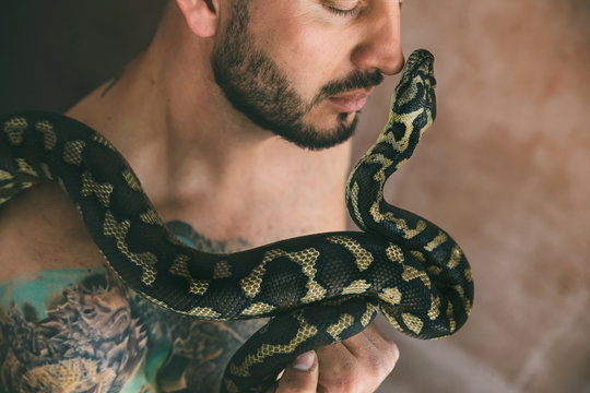 Portrait of man holding a snake near his face