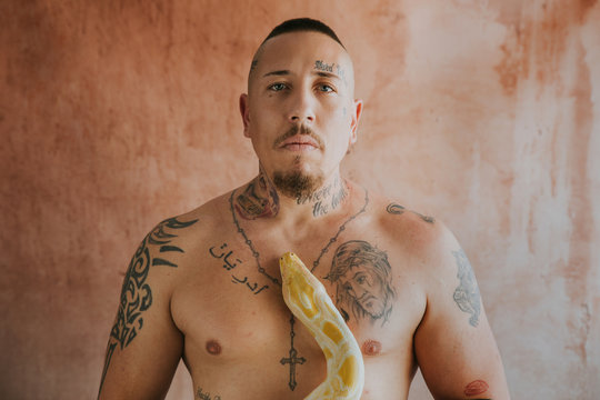 tattooed man looking at camera with a snake on his chest