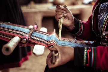 Woman weaving alpaca wool with bone