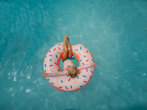 little girl sitting in pool with donut pool float