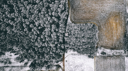 Aerial view of forest and field with first winter snow