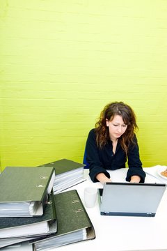 Caucasian young woman working on her laptop computer at her desk