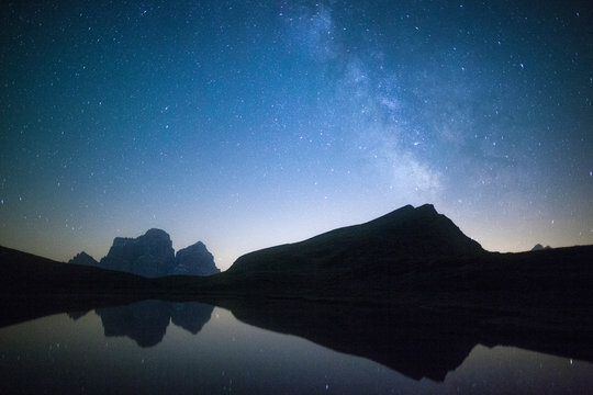 Milky way and stars on Pelmo mirrored in Baste Lake, Dolomites, Italy