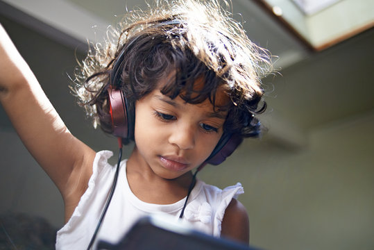 Cute little black girl wearing headphones watching Youtube videos