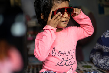 Adorable cute girl wearing sunglasses and making fun at indoors