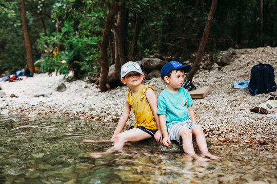 Young girl and boy sitting on rock in water at Barton Springs