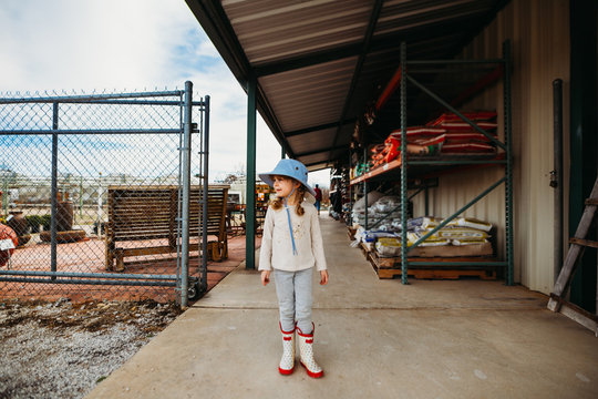 Young Girl Standing Outside Garden Center Wearing Sun Hat