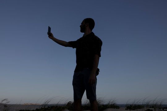 People and internet technology man looking for signal with a mobile phone device - people traveling for adventure concept and alternative vacation - blue sky