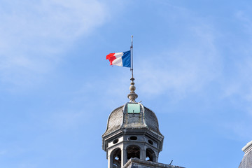 French national flag in a mast on top of an ancient dome, against a blue sky