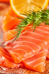 Raw salmon fillets with pepper salt dill lemon on wooden board. Close up.