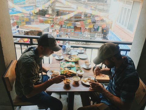 Two young men eating colorful meal on rooftop in Asia