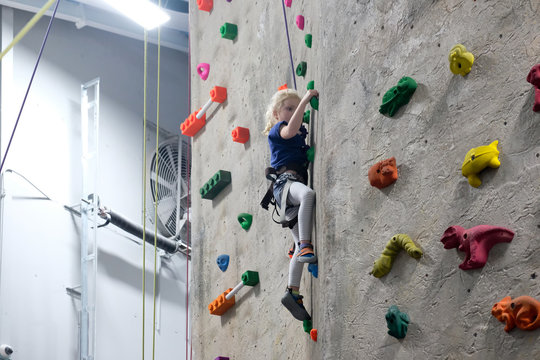 young girl climbing rock wall at indoor rock  climbing gym