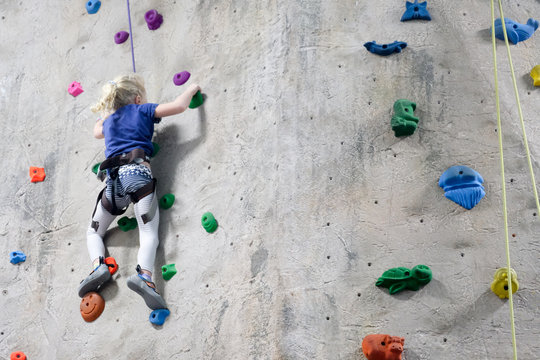 young girl climbing rock wall at indoor rock  climbing gym