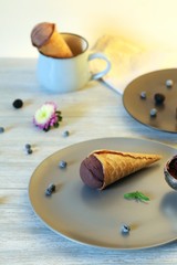 Homemade chocolate ice cream in waffle cones, berries on a wooden table, healthy dessert